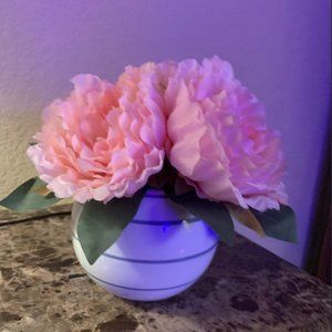 light pink faux flowers in a white and light navy blue striped round vase